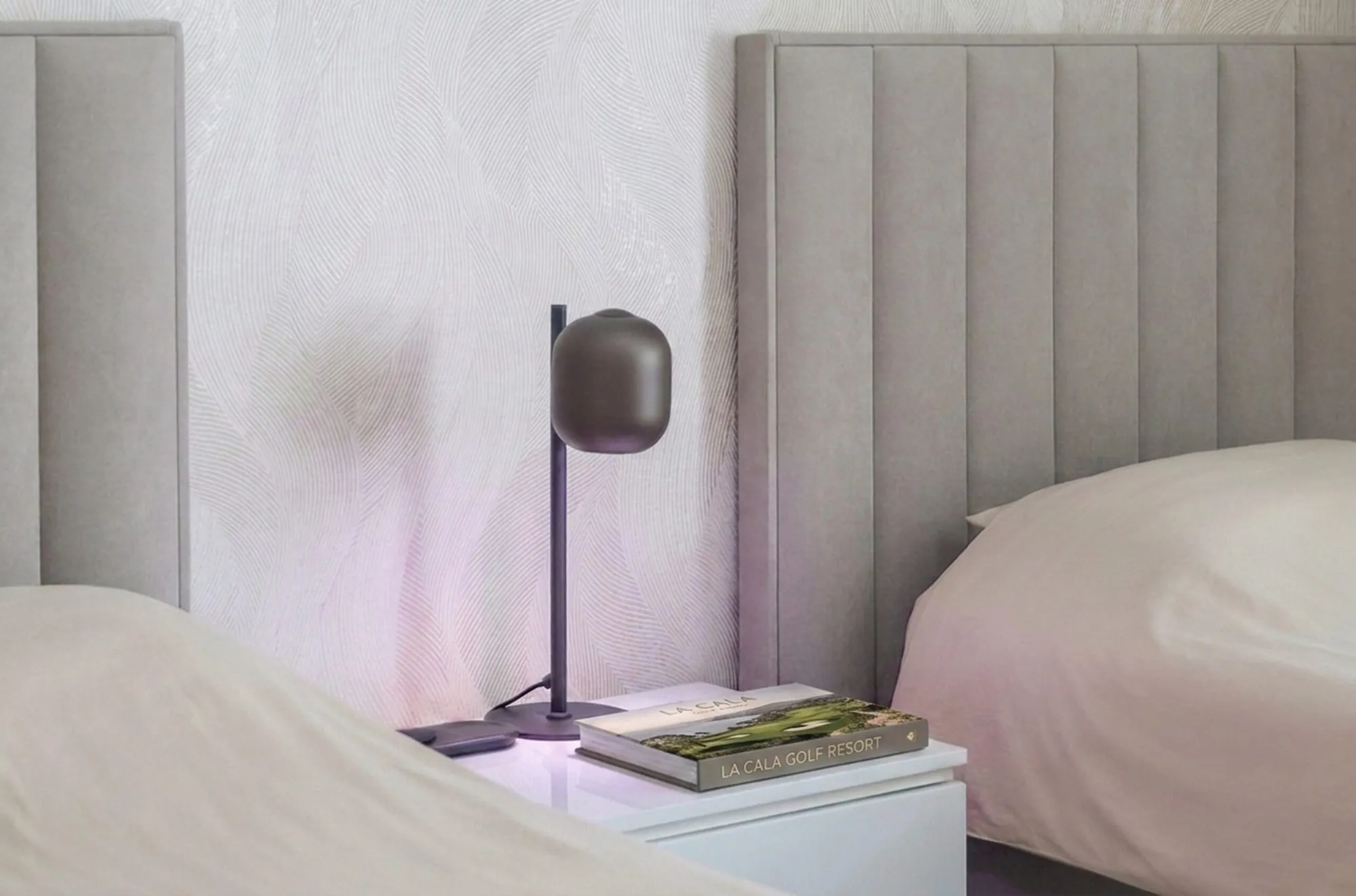 Nachtkastje met leeslamp tussen twee eenpersoonsbedden, met een boek over La Cala Golf Resort
